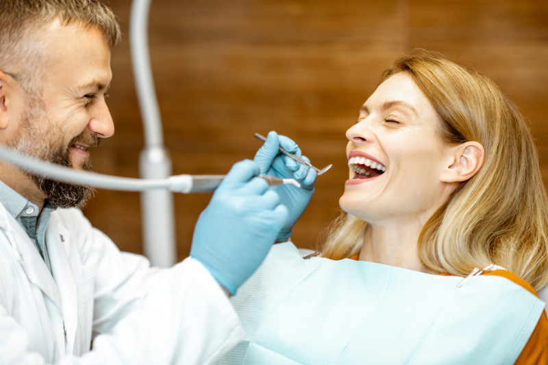 Smiling dentist and patient starting teeth cleaning